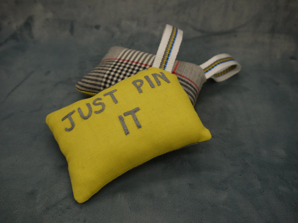 Pin cushion in yellow and grey wool, superfine 120, Just Pin It Embroidered by hand in grey on a yellow background, Nylon wriststrap with yellow/blue go stripe, Prince of Wales wool backing in white and black