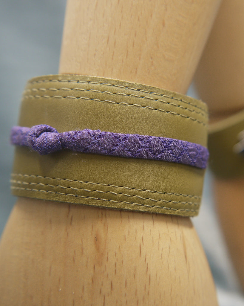 Olive green slimline Italian leather cuff with royal purple slim silk  knot central on the cuff. The cugff has elegant repeat stitch detail around the edges. Close-Up Image