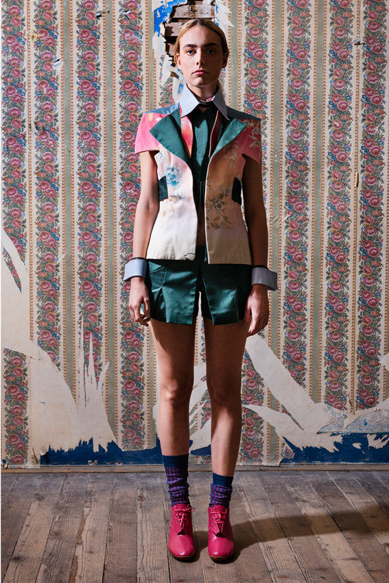 Model wears Unique outfit from the Wallflowers Collection Kimono tailored waistcoat jacket in cotton and silk and pleated shorts. She is also wearing blue/grey leather shirt collar and cuffs