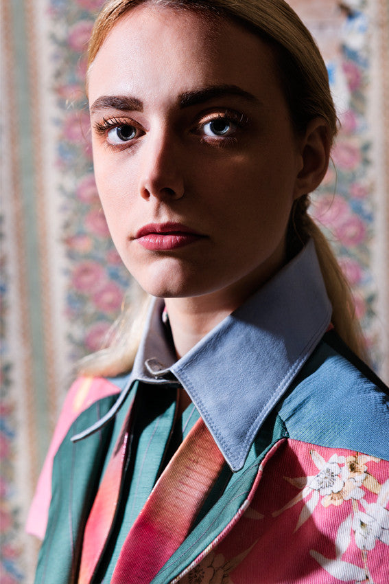 Model Wallflowers photoshoot wears Pale blue leather shirt collar over Leather Degradè rose coloured leather undone bow-tie. Close-Up image